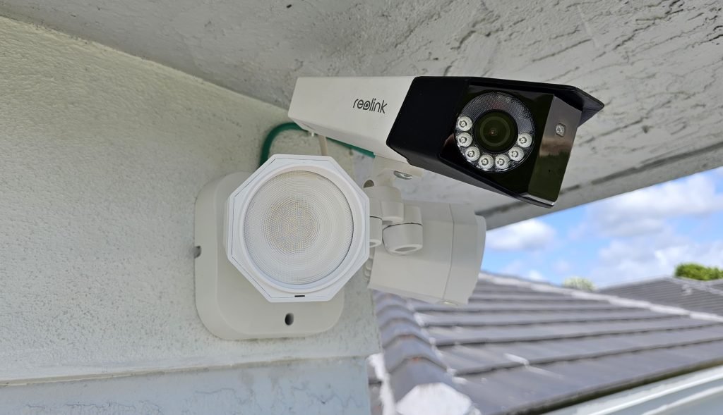 Cámara de seguridad REOLINK Duo 3 PoE instalada en una pared exterior con vista panorámica y diseño moderno.